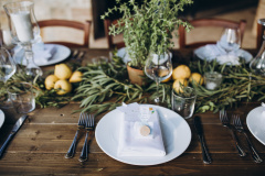 in the back yard of the old villa there is a long festive table, which is decorated with lemons and herbs, on the table are plates, glasses and candles. Wedding in Italy. Tuscany