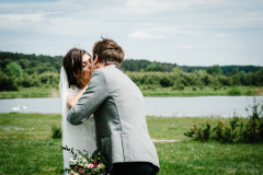 The first meeting and first kiss is newlyweds on a green field outdoors. Bride goes back to the groom, surprise in nature. The woman closed her eyes to her husband. Happy wedding day of marriage.
