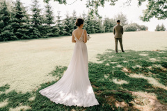 First meeting. Bride goes, back to the groom, surprise. Groom waiting for his bride. A young man in suit holding bouquet of flowers and stand on the terrace, backyard.